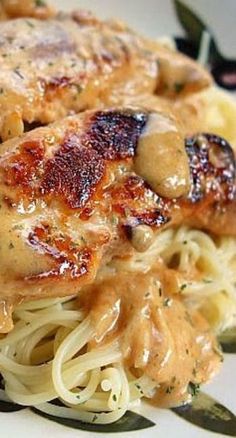 a pasta dish with chicken and gravy is shown on a white and black plate