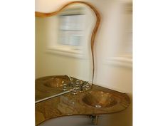 a bathroom sink sitting under a mirror next to a counter top with two faucets