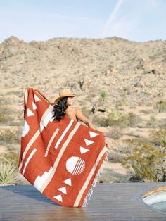 a woman wrapped in a red and white blanket sitting on top of a wooden table