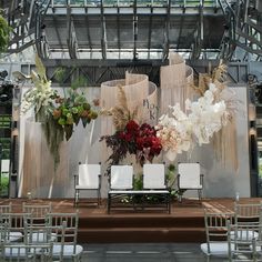 an arrangement of flowers and chairs in front of a stage set up for a wedding