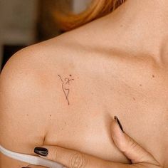 a woman's shoulder with a small tattoo on the left side of her breast