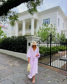 a woman in a pink robe and hat walking down the street