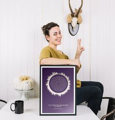 a woman sitting at a table holding up a purple poster with a spiral design on it