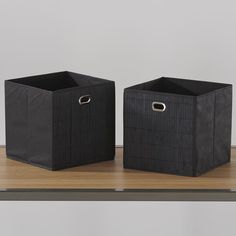 two black bins sitting on top of a wooden table