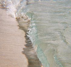 an ocean wave coming in to the shore with white foamy water on it's surface