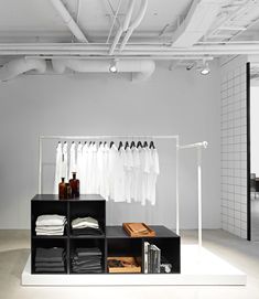 an empty room with clothes hanging on the rack and other items in front of it