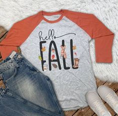 Cute Hello Fall t-shirt with 3/4 length sleeves Super soft grey heather cotton/poly blend shirt with orange or black sleeves This 3/4 sleeve tee is a super soft blend which is 65% polyester/35% cotton Very soft and easy to care for. Sizing Info: Available in size XS - 2XL. This is a Unisex shirt, so women will typically order a size smaller than usual. See sizing chart for measurements. This design is also available in a short sleeve t-shirt here: Printed material is applied to the shirt with su Baseball Tees For Women, Black Sleeves, Baseball Tees, Hello Fall, Raglan Tee, Tees For Women, Hello Autumn, Sizing Chart, Unisex Shirt