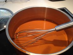 an orange pan with whisk in it sitting on top of a stove