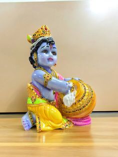 a statue of a person sitting on top of a wooden floor next to a wall