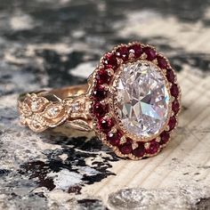 a fancy ring with an oval cut diamond surrounded by red and white stones on a rock