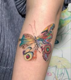 a woman's arm with a colorful butterfly tattoo on the left side of her arm