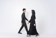 two people dressed in black walking side by side, one holding the other's hand