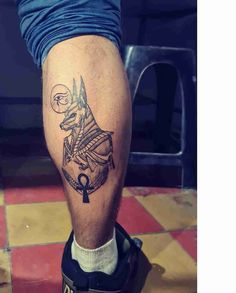 a man's leg with an egyptian tattoo on it and a key in the middle