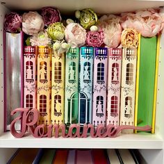 a shelf filled with lots of different colored books and flowers on top of each other