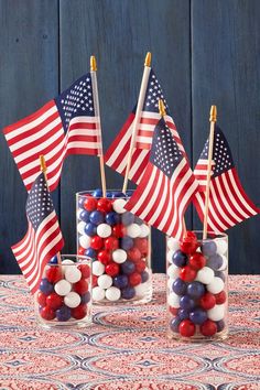 three vases filled with red, white and blue candies next to american flags