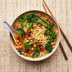 a bowl filled with noodles, broccoli and chickpeas next to chopsticks