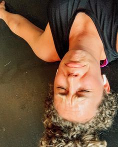 a woman is upside down on the ground with her hair blowing back and eyes closed