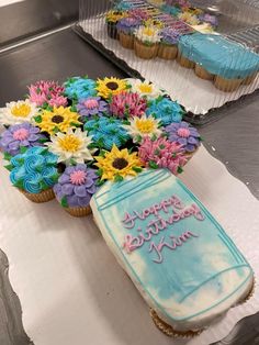 cupcakes with frosting and flowers are on display