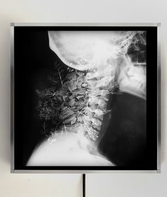 a black and white photo of a man's neck with flowers on it, in front of a wall