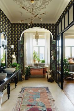 an ornately decorated bathroom with black and gold wallpaper, antique sink, mirror, rug and chandelier