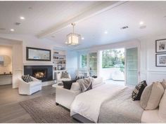 a large white bed sitting inside of a bedroom next to a fireplace in a living room