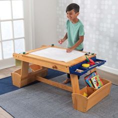 a young boy is playing with his drawing table