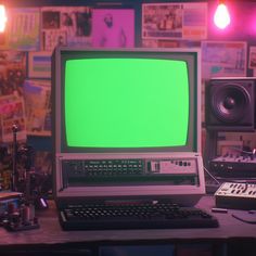 a laptop computer with a green screen sitting on top of a desk in front of sound equipment