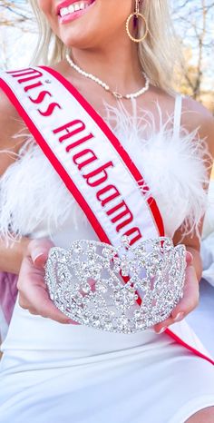 a woman in a white dress holding a tiara