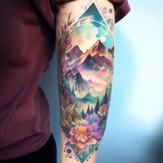 a person with a tattoo on their arm that has mountains and flowers in the background