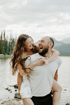 a man and woman hugging each other by the water