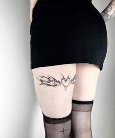 a woman with tattoos on her thigh wearing stockings