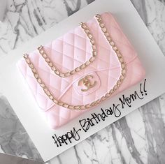 a pink birthday cake with a chanel bag on it