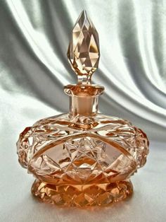 an orange glass perfume bottle sitting on top of a table