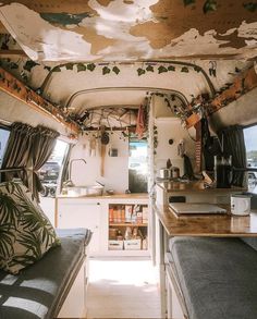 the interior of a camper with plants growing on the ceiling and kitchen in the back