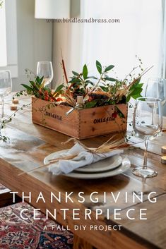 a thanksgiving centerpiece is displayed on a table with wine glasses and place settings in wooden boxes