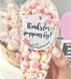 a person holding a bag of pink and white popcorn