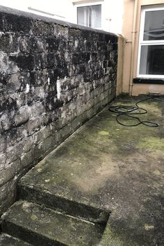 an old brick wall and steps in front of a window with a hose attached to it