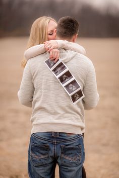 a man and woman hugging each other in the middle of a field with an old film strip attached to their back