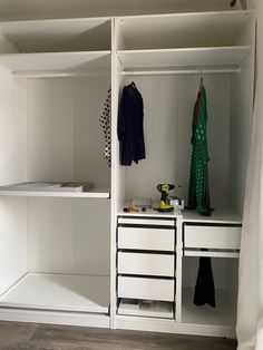 a white closet with drawers and clothes hanging on the wall