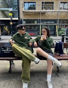 two people sitting on a bench drinking beverages