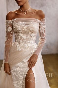 a woman in a white wedding dress with sheer sleeves and thigh high slits posing for the camera