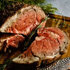 sliced roast beef on a cutting board with rosemary sprigs and seasoning next to it