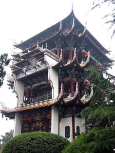 a tall building with lots of decorations on it's roof and windows in front of some trees