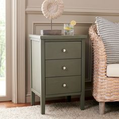 a small table with two drawers next to a wicker chair in a living room