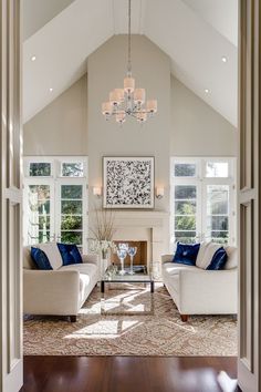 a living room filled with furniture and a chandelier hanging over the fire place