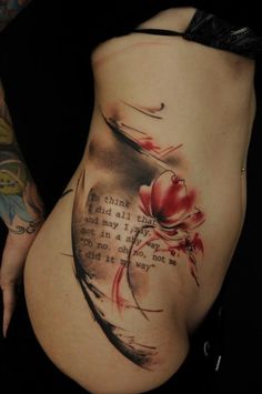 a woman's stomach with an inked quote on the side, and flowers