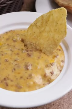 a white plate topped with a tortilla chip and cheese dip