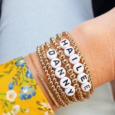 the bracelets are stacked on top of each other and have letters that spell out happy