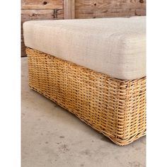 a wicker bench with cushion on the top and bottom, in front of some wooden drawers