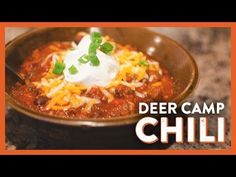 a bowl of chili with sour cream on top and the words deer camp chili above it